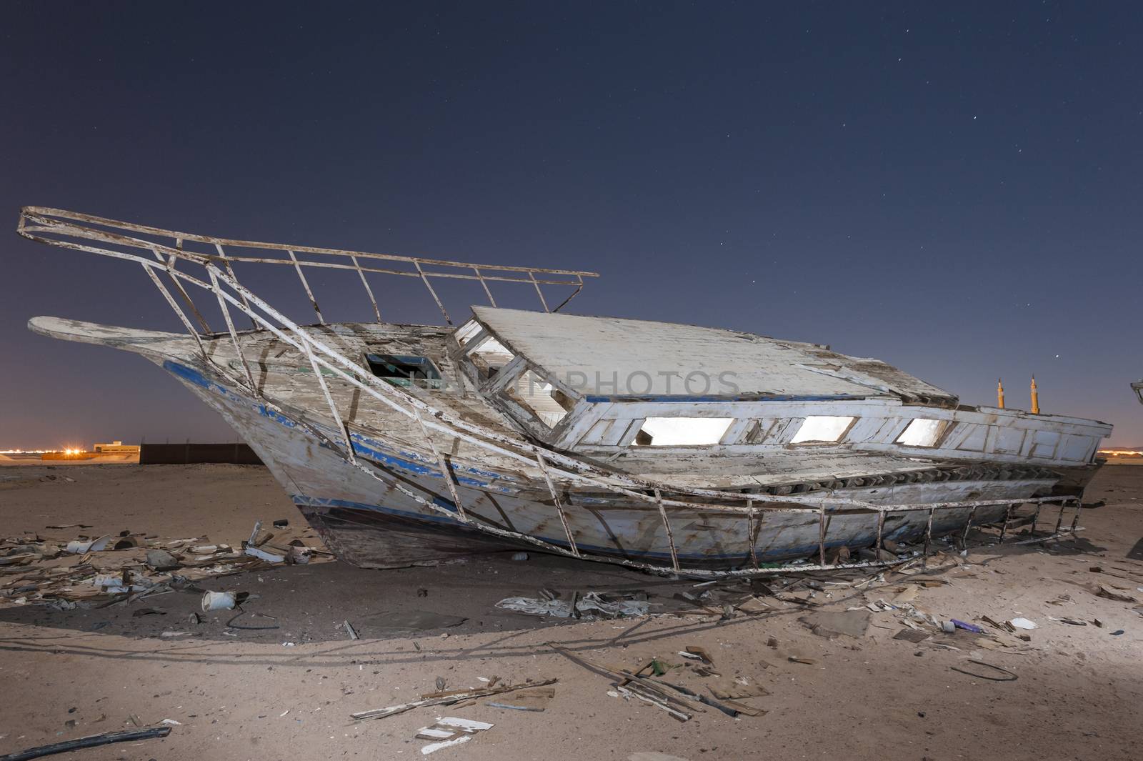 Abandoned derelict wooden boats in the desert under a night sky with abstract lighting effects