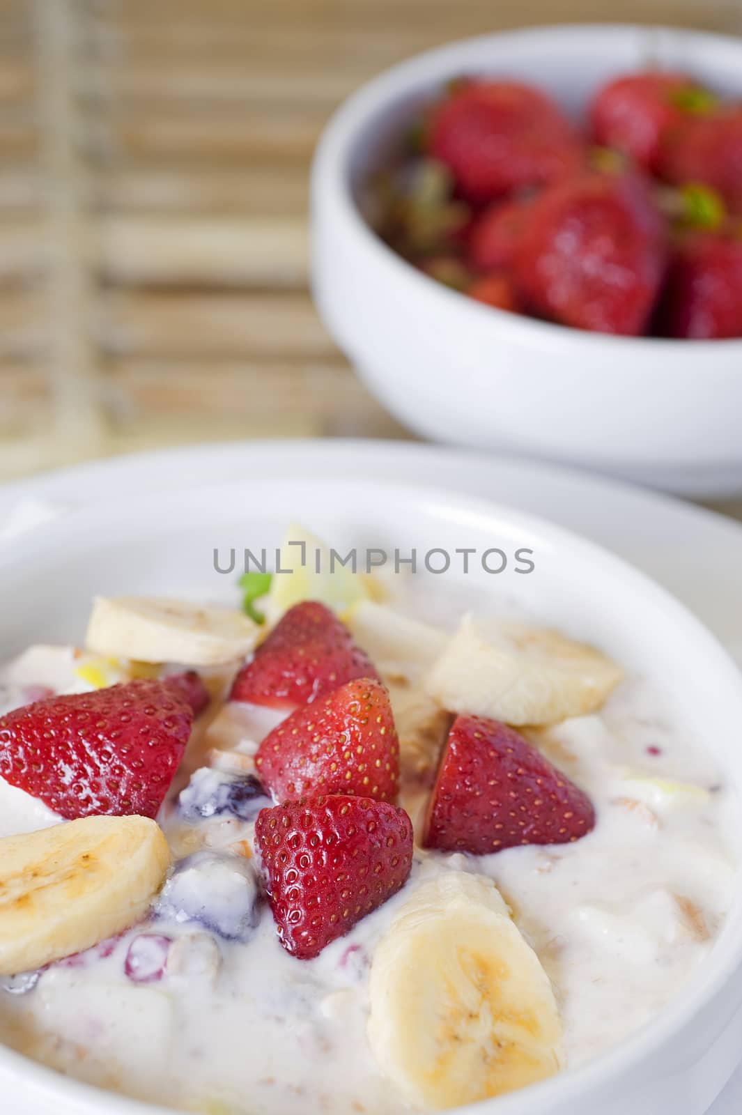 Fresh fruit salad in a white dish with fresh strawberries