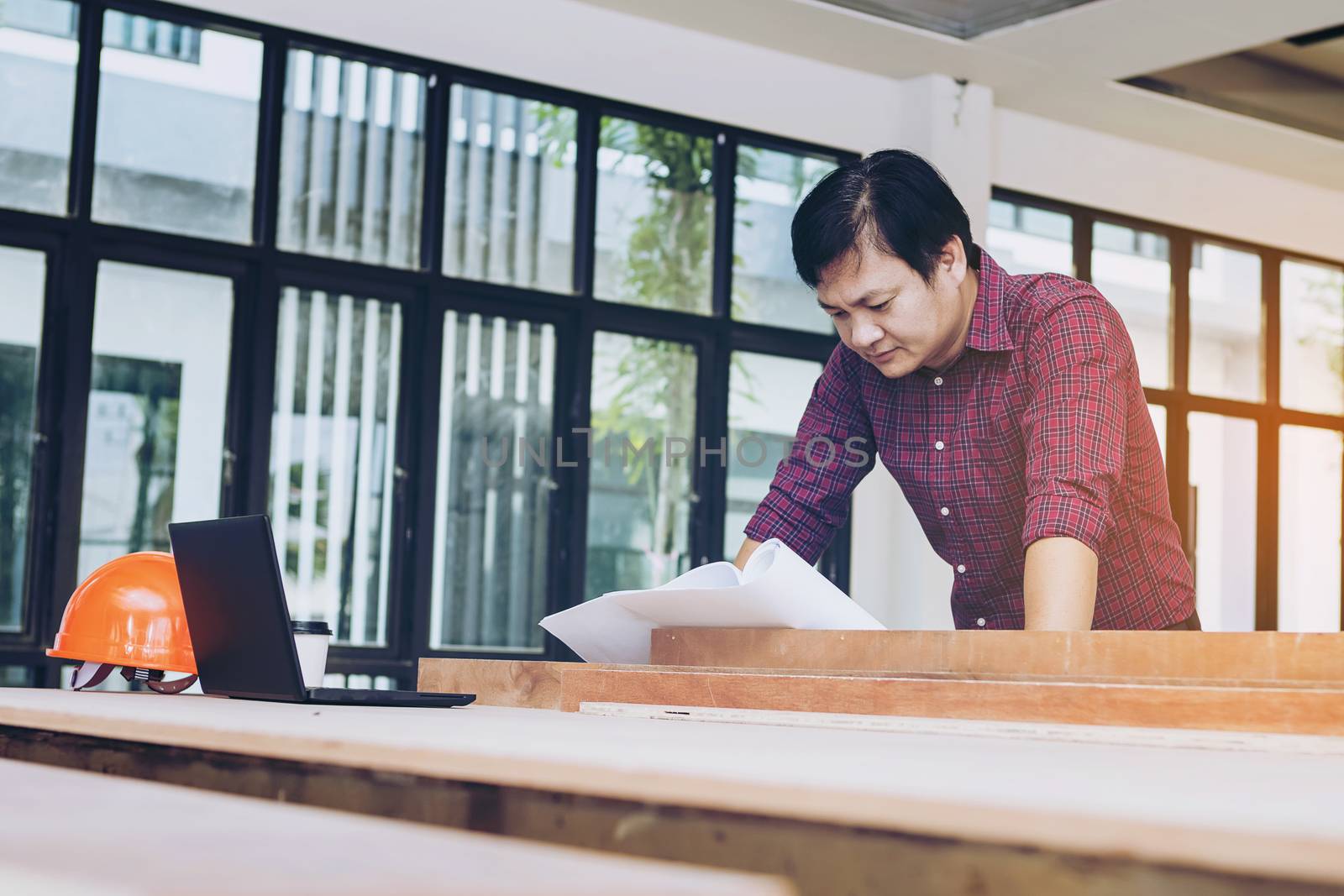 Two engineers are working on a blueprint. With work space