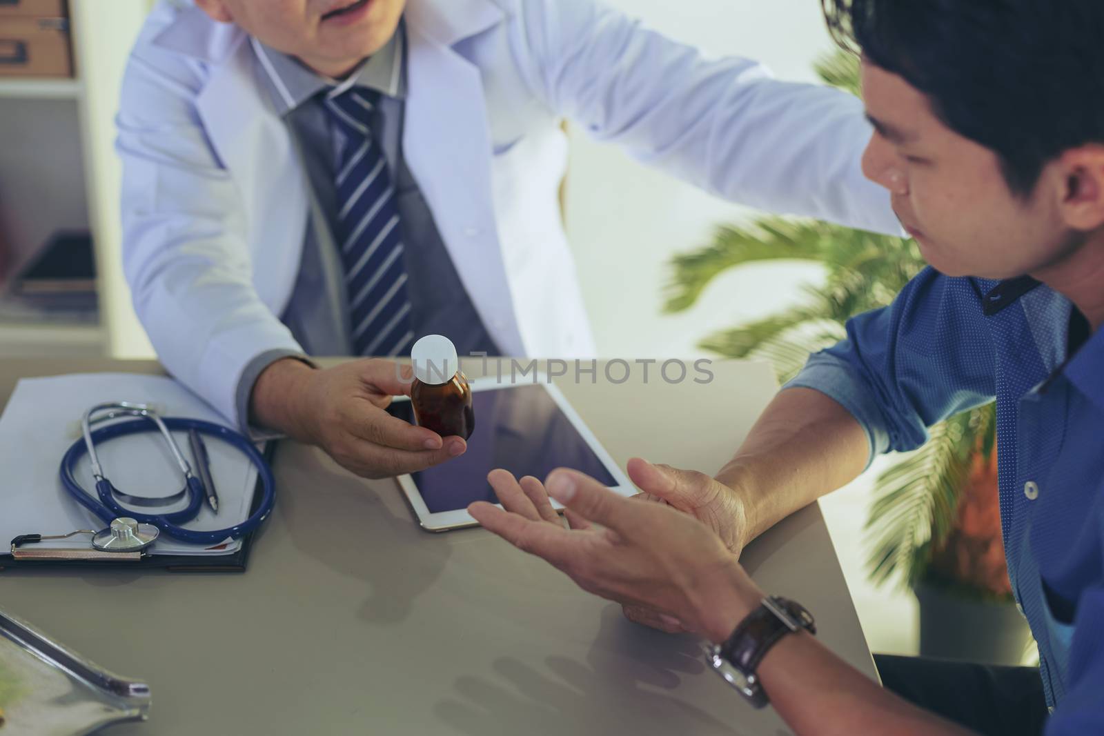 The doctor is explaining something about the medicine to the patient, in order to understand how to use it and to know the benefits and penalties of the drug.
