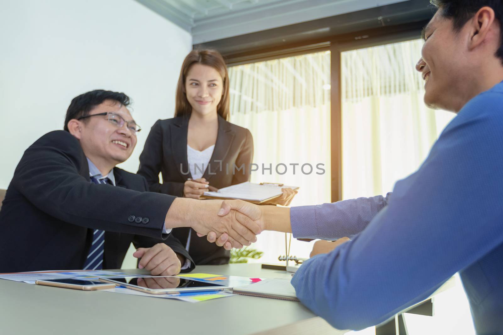 Business people handshake, businessmen hand shake, during meeting signing agreement sitting at desk team work group on conference discussing financial diagram, graph, business charts