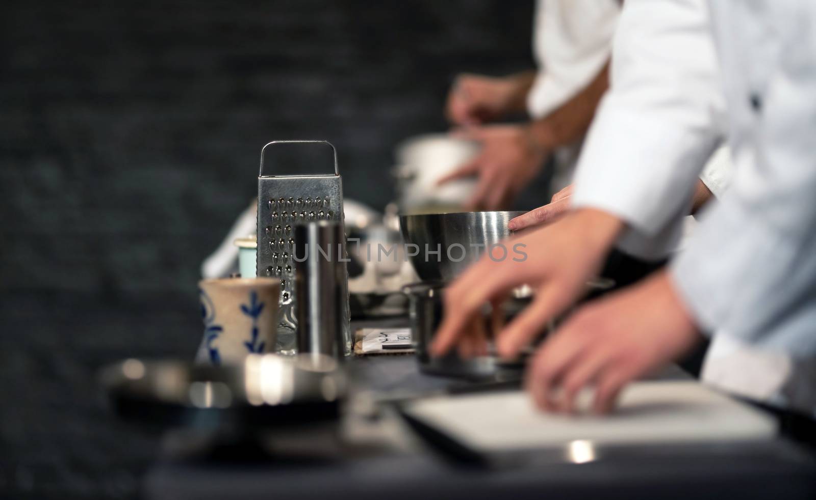 Team of professional chefs preparing food in a commercial kitchen. Cooks in the production process of system catering. An inside view of a pro catering kitchen in Spain. Extreme narrow depth of field.