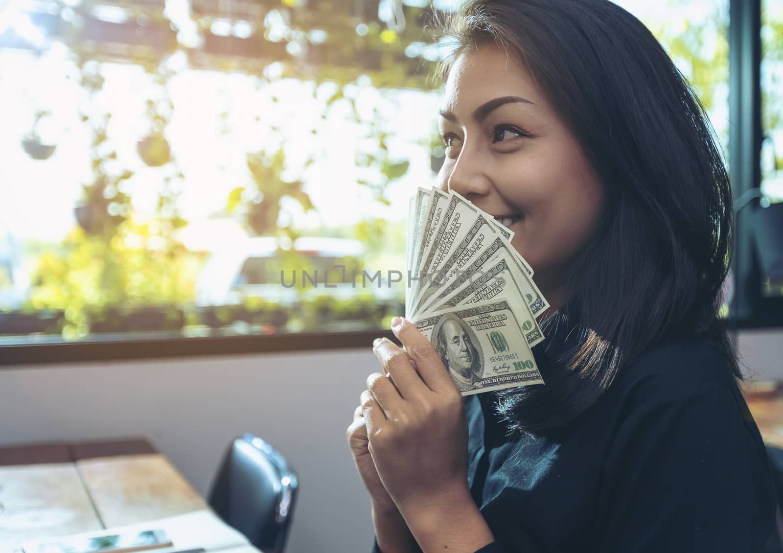 Portrait of a young surprised businesswomen with much money after signing the contract. Beautiful young businesswoman in black shirt holding money in hand and happy smile