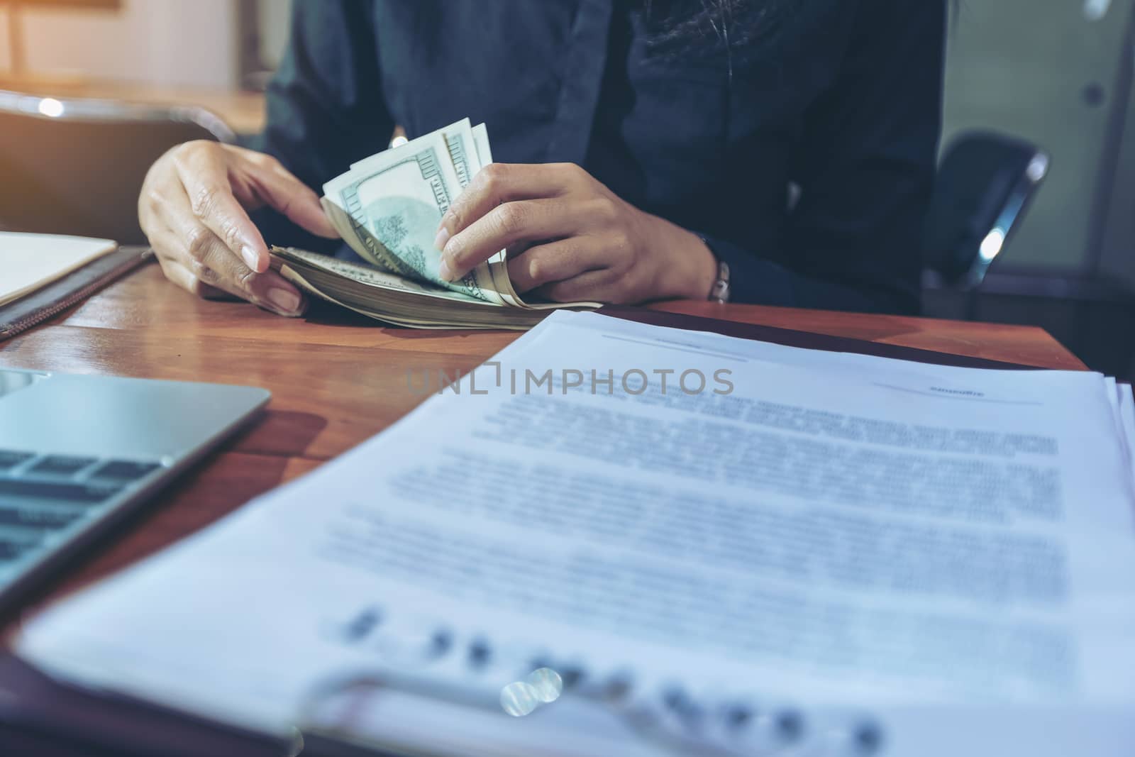 Portrait of a young surprised businesswomen with much money after signing the contract. Beautiful young businesswoman in black shirt holding money in hand and happy smile