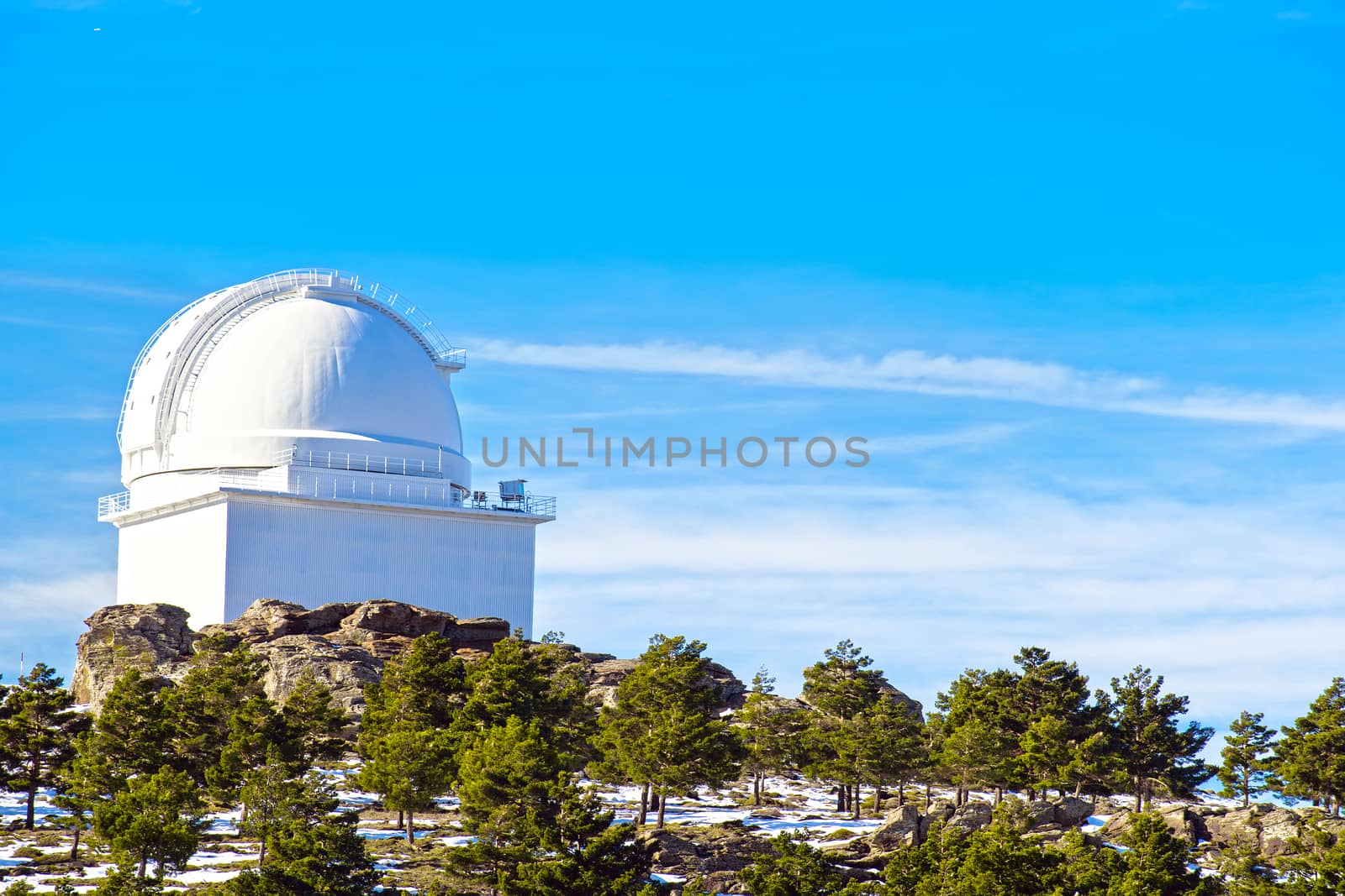 View of Calar Alto Observatory at the snowy mountain top in Almeria, Andalusia, Spain, 2019. Sky passing through against the domes
