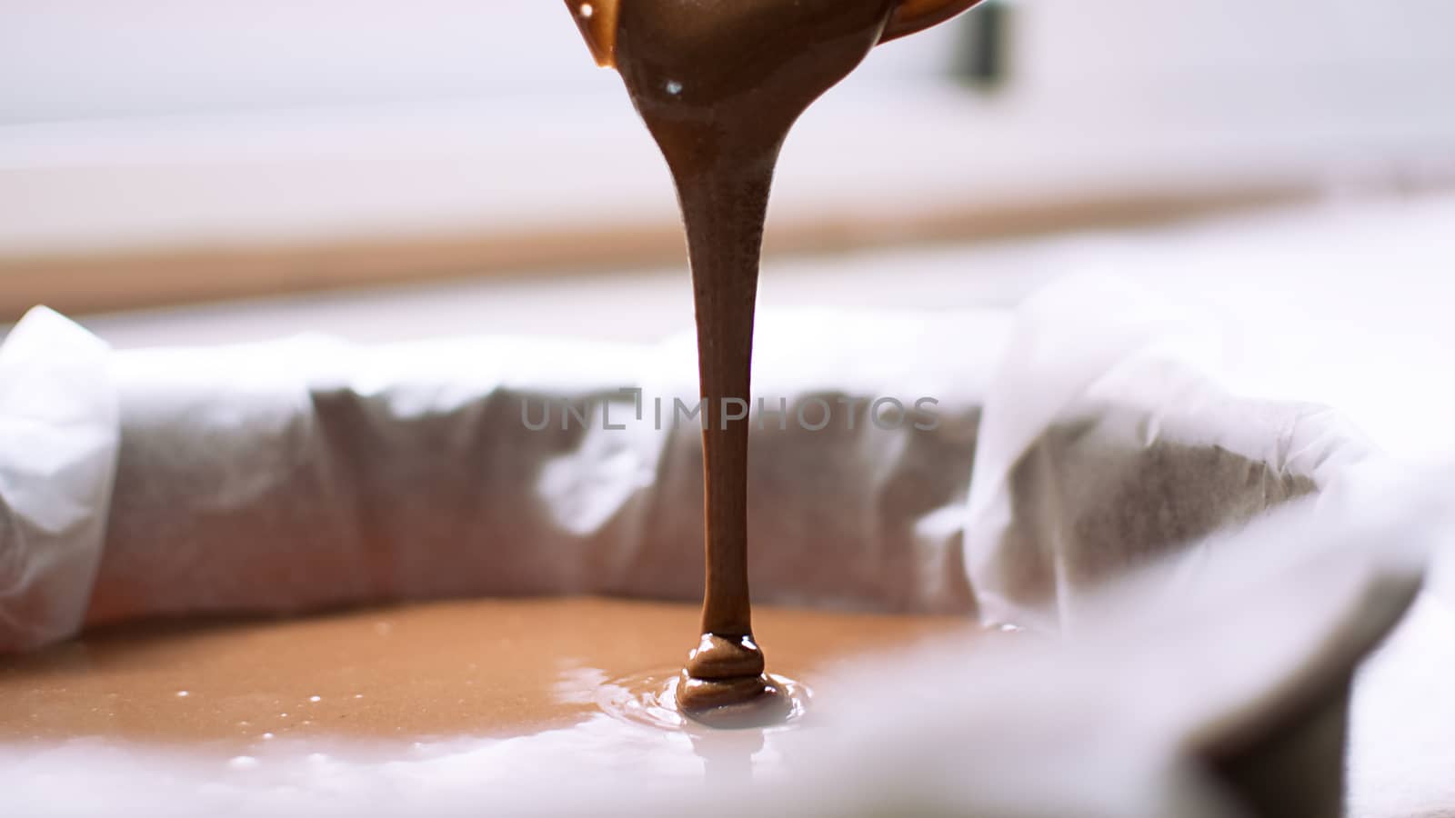 A close-up of chocolate milk liquid being poured into the form of a confectionery syringe in the form mold or mould. Preparation of chocolate sweets, biscuits, cooking process