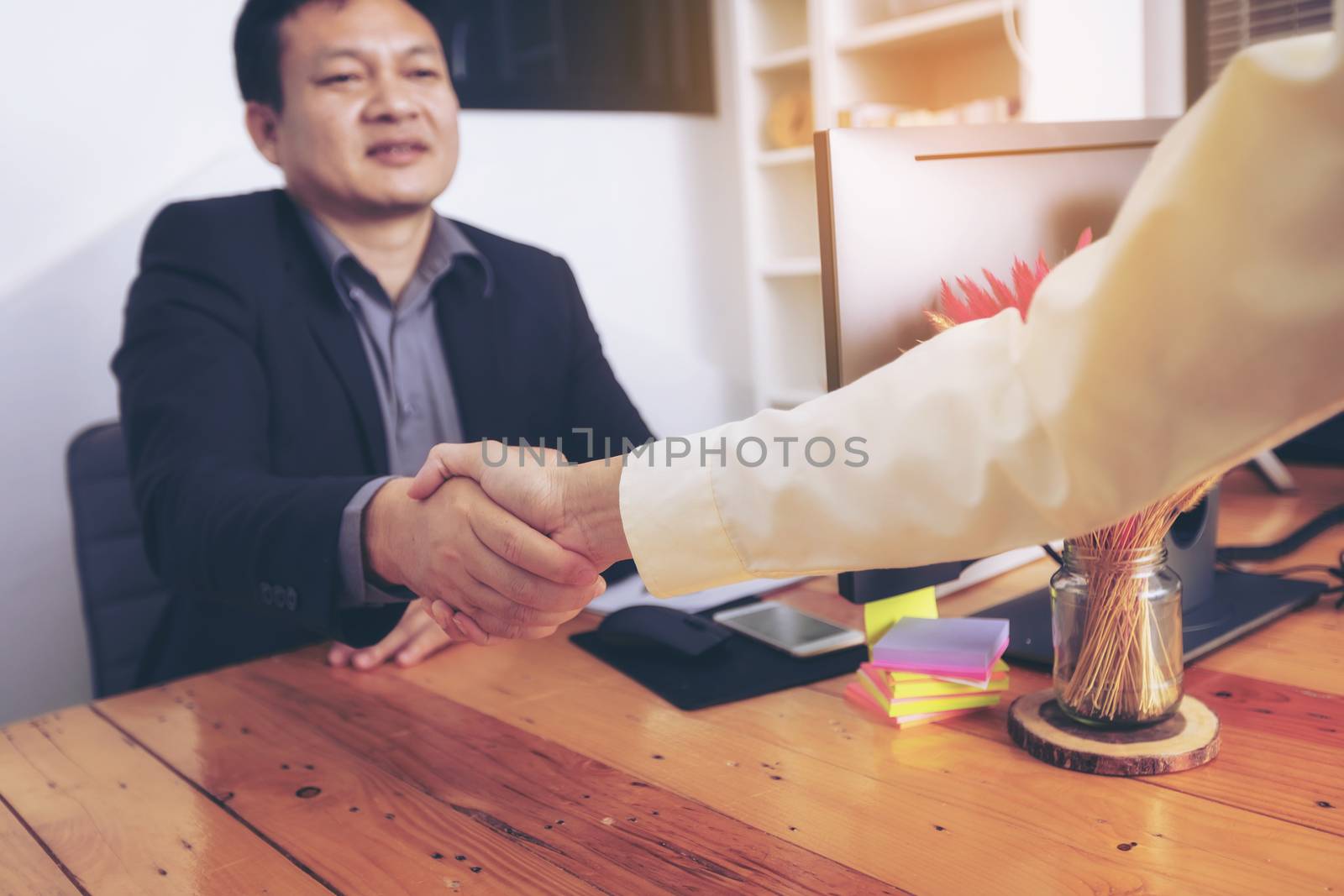 Businesspeople and partners shaking hands over the table, maintaining eye contact, confident entrepreneurs ready for effective negotiations, entering into a partnership, gender equality