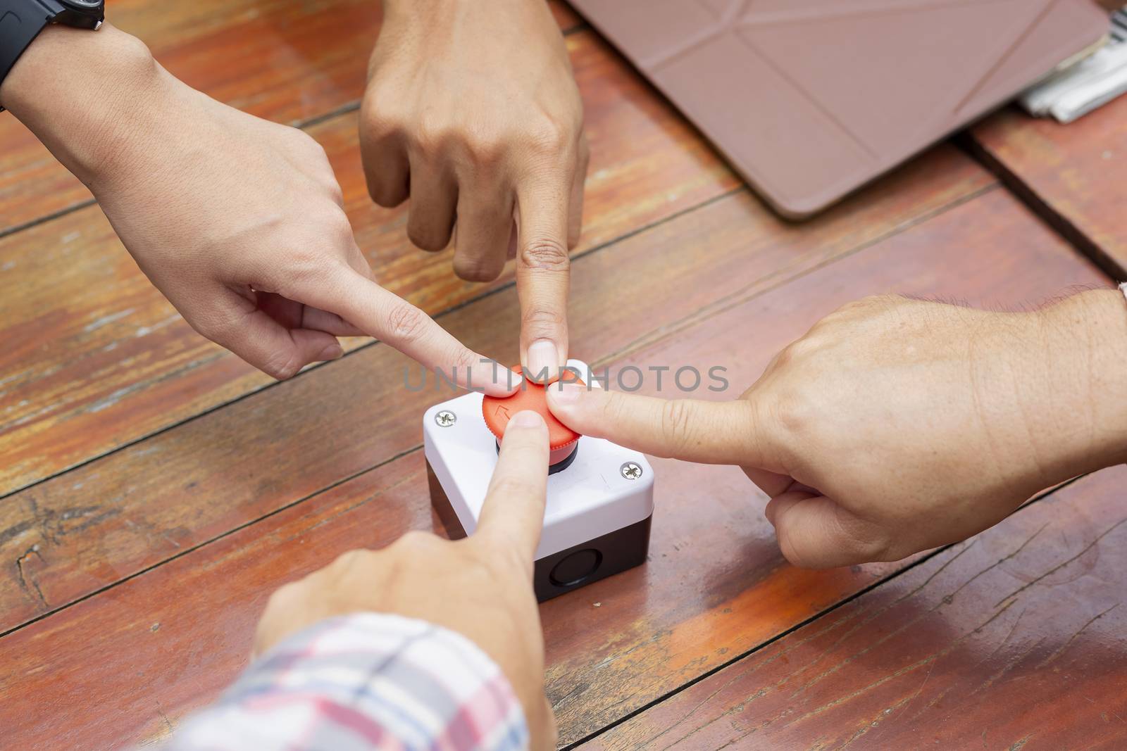 Multiple hands join for push the emergency stop button for stop circuit system. Concept of stopping environmental destruction