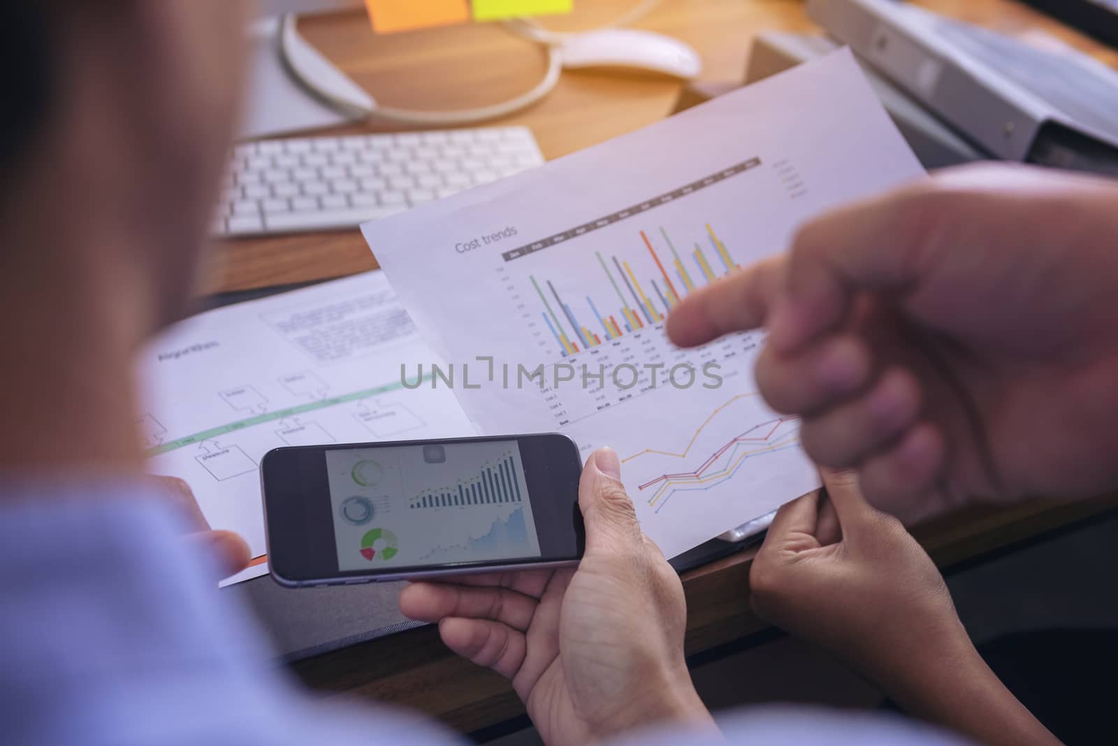 Businessman giving presentation on  mobile phone screen to colleagues in office. Business meeting time. Idea presentation, analyze plans.