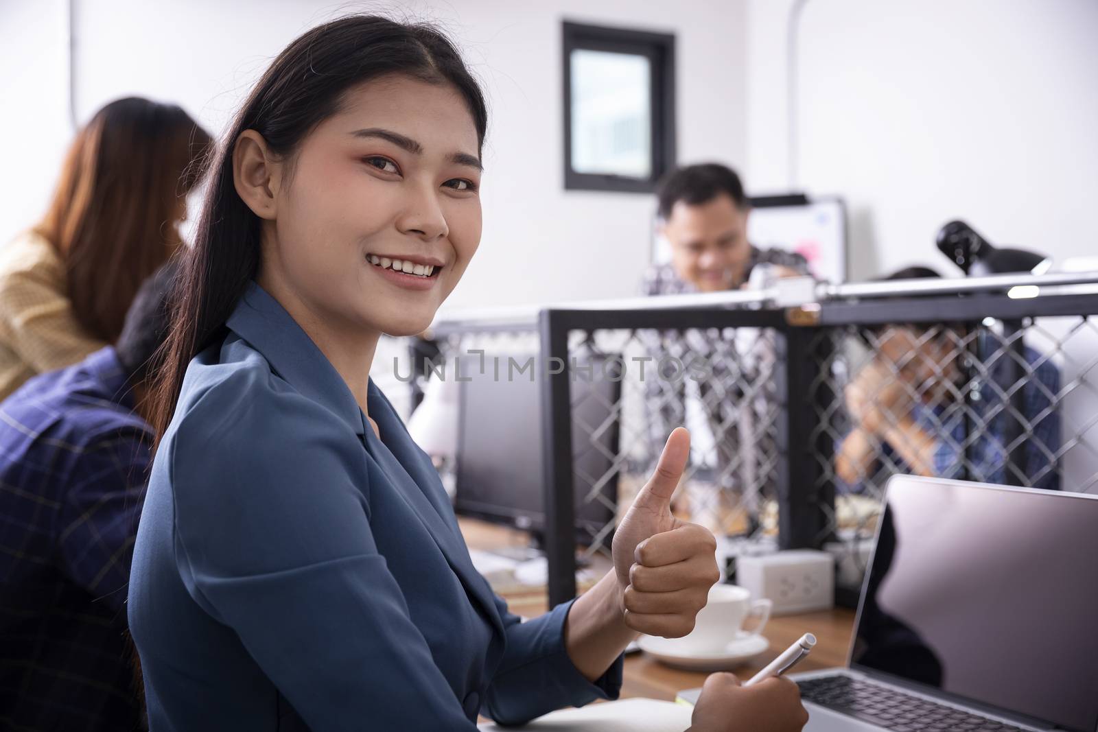 Beautiful young businesswoman excited with his success giving thumbs up to the laptop. Businesswoman showing thumbs up