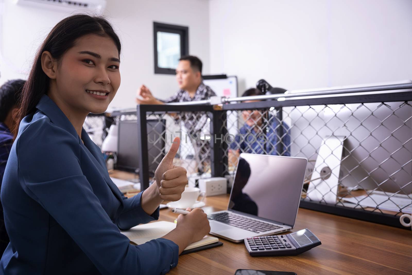 Beautiful young businesswoman excited with his success giving thumbs up to the laptop. Businesswoman showing thumbs up