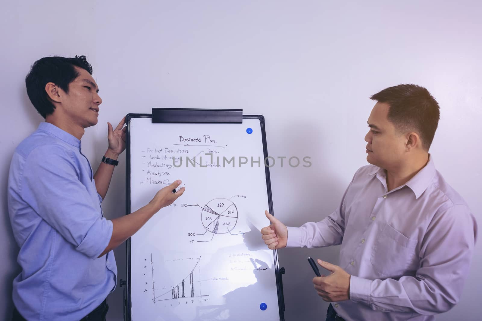 Young businessman writing on white board in conference room to planning of the agency. Business meeting presentation concept
