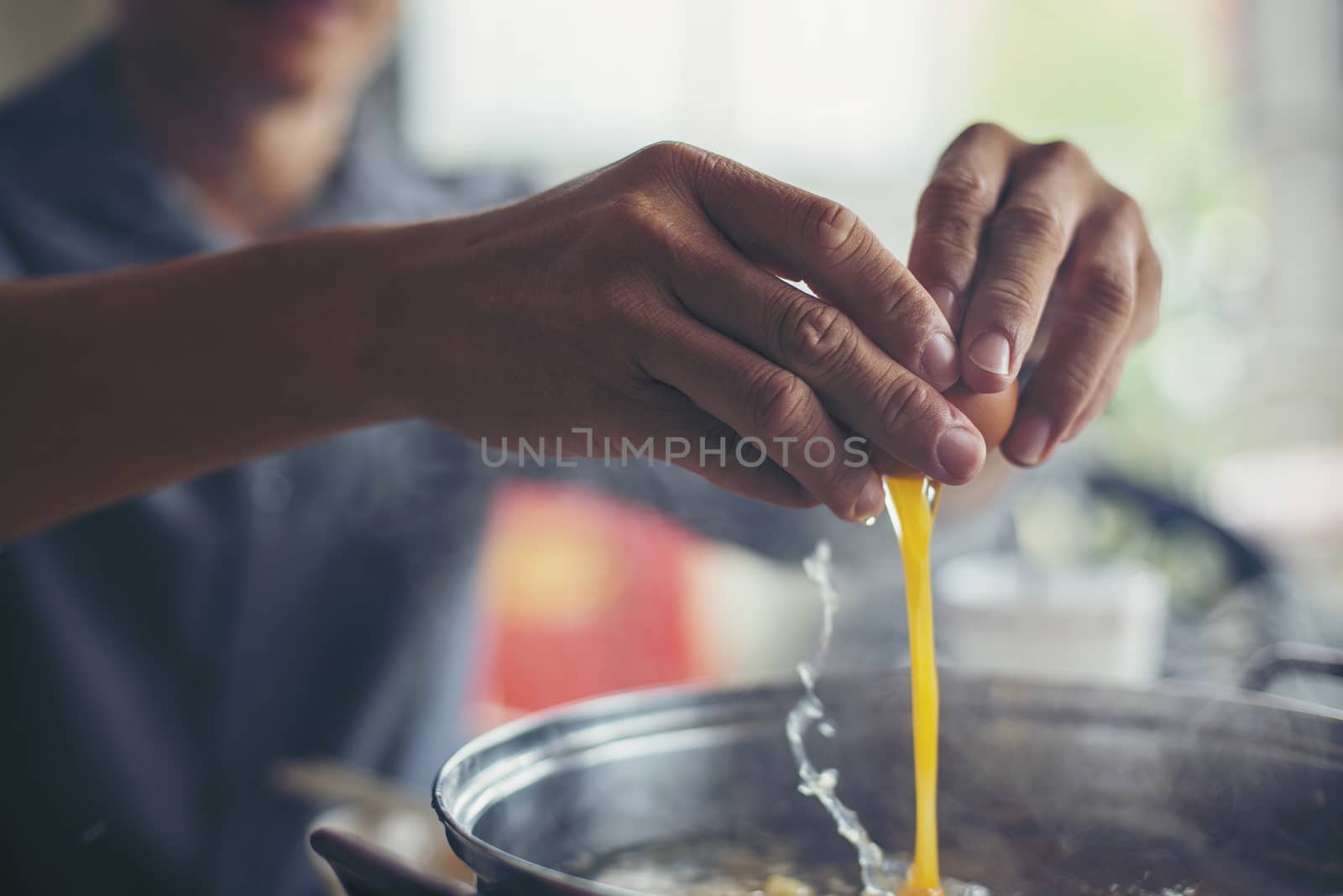 The hand that holds the egg is put into a sukiyaki pot.