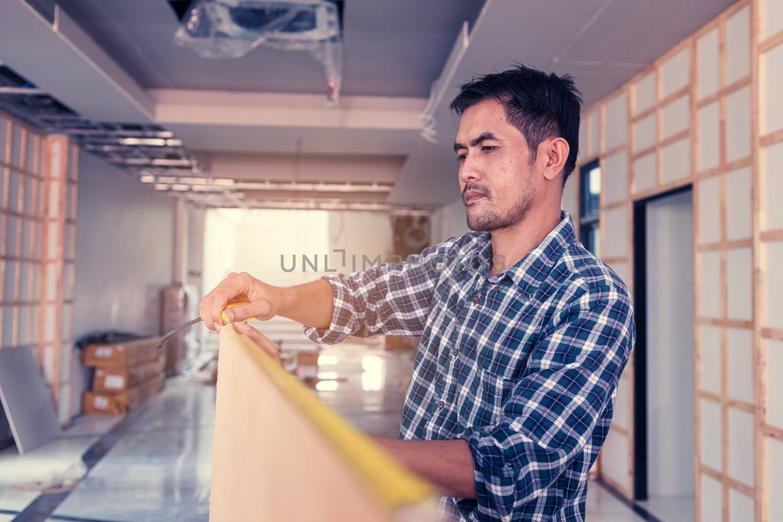 The carpenter is using a tool to measure the size of the wood for use in his work.