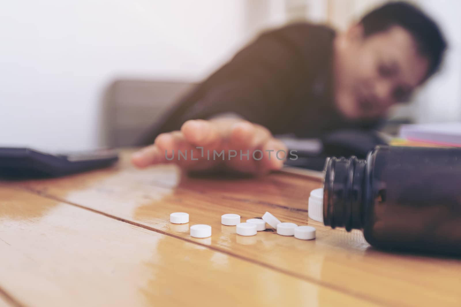 Stressed businessman having severe headache, holding painkiller remedy pill. Stress job