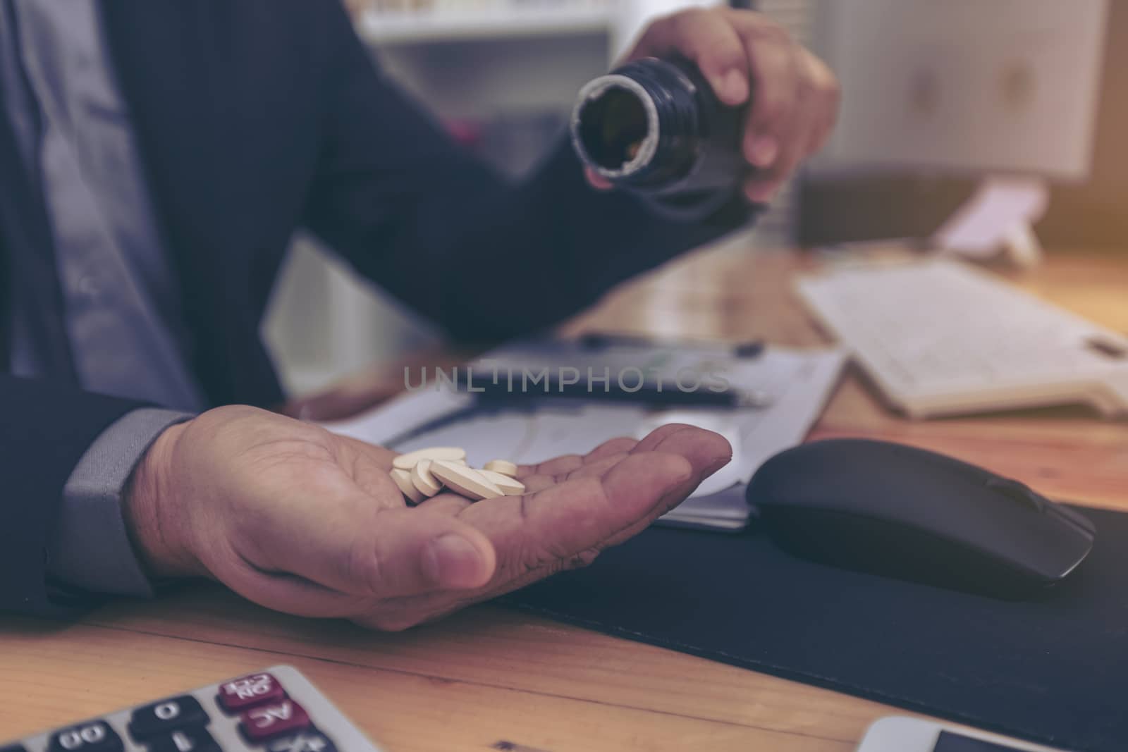 Stressed businessman having severe headache, holding painkiller remedy pill. Stress job