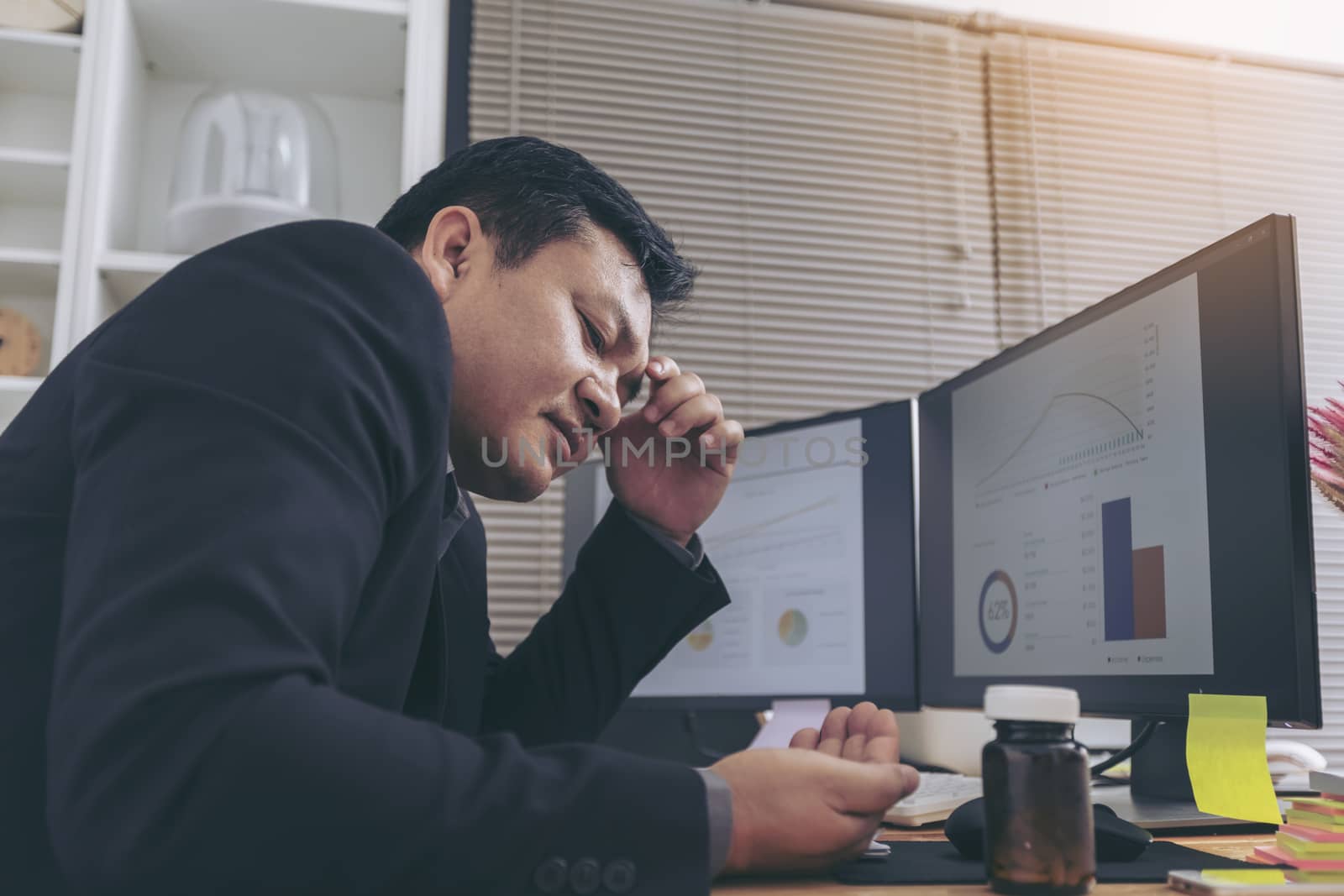 Stressed businessman having severe headache, holding painkiller remedy pill. Stress job