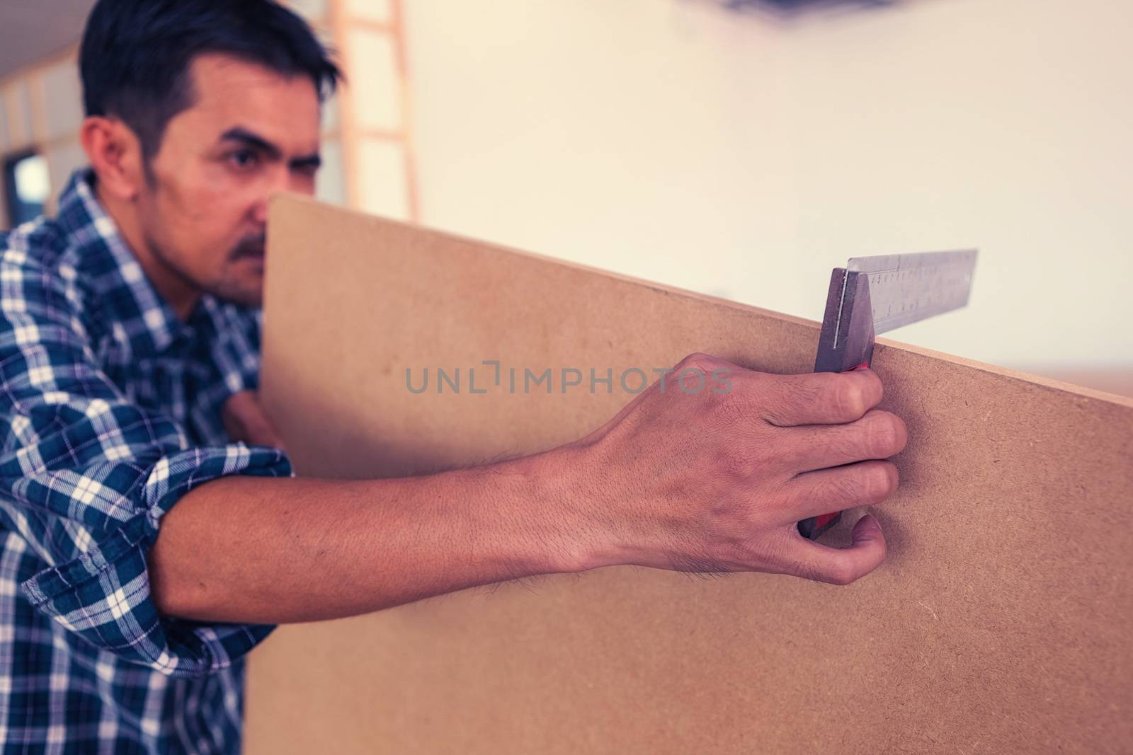 The carpenter is using a tool to measure the size of the wood for use in his work.