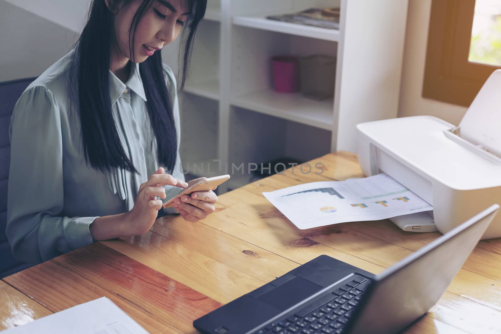 Beautiful young businesswoman doing some paperwork while sitting at office desk in front of computer.