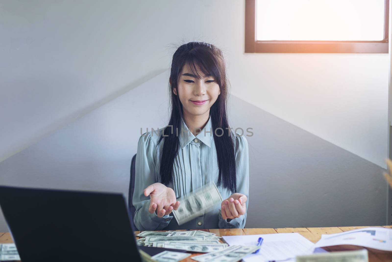 Successful business women are counting money and throwing a dollar at work happily.