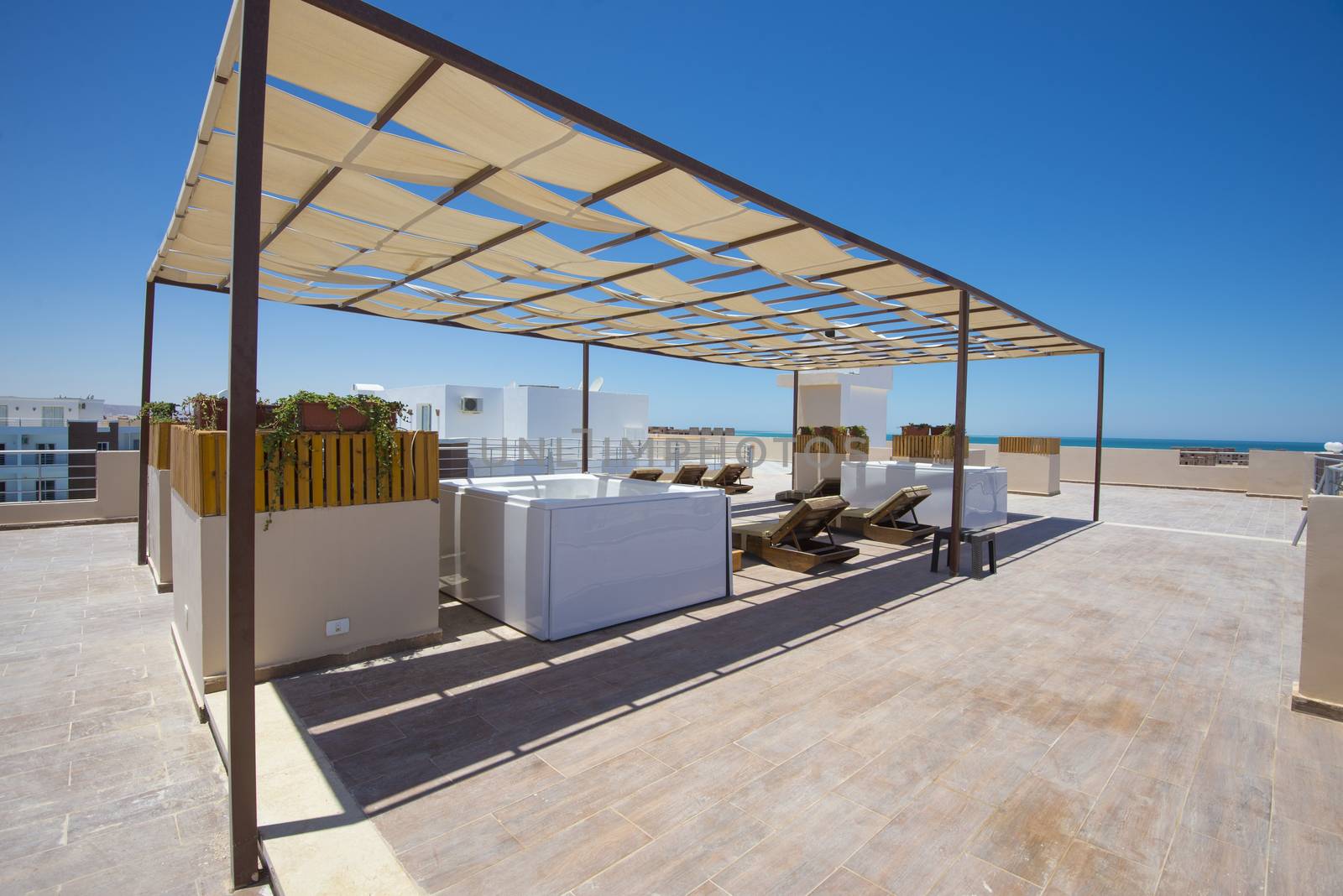 Sunbeds and hot tubs on roof terrace patio sunbathing area of luxury hotel apartment building