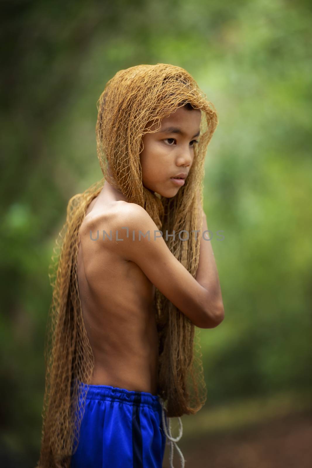 The image of a young man using a fishing net to cover his head and taking off his shirt. country young boy portrait in outdoors,Happy rural young boy smiling in field,portrait of a happy young asian young boy.