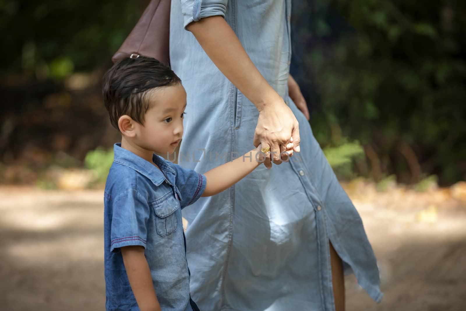 Happy mother and adorable little boy enjoying warm weather at beautiful park