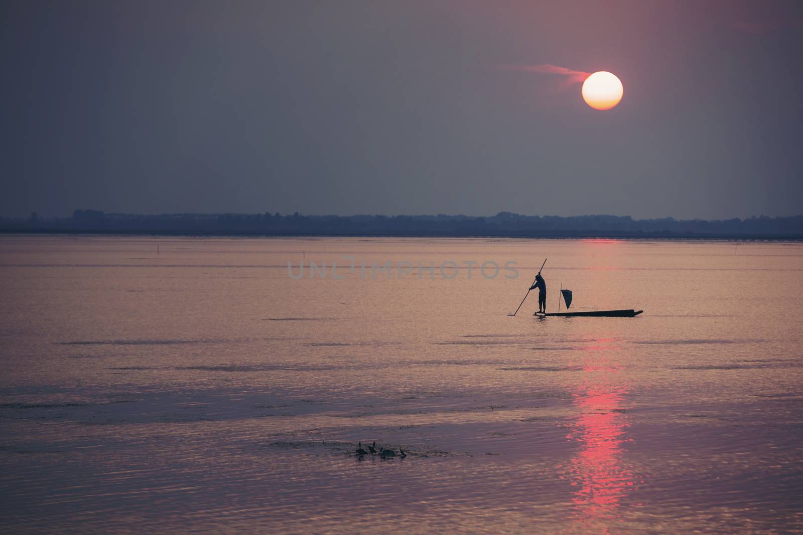 Fishermen make a living by using traps to catch fish that have nets like catching fish during the sunset.