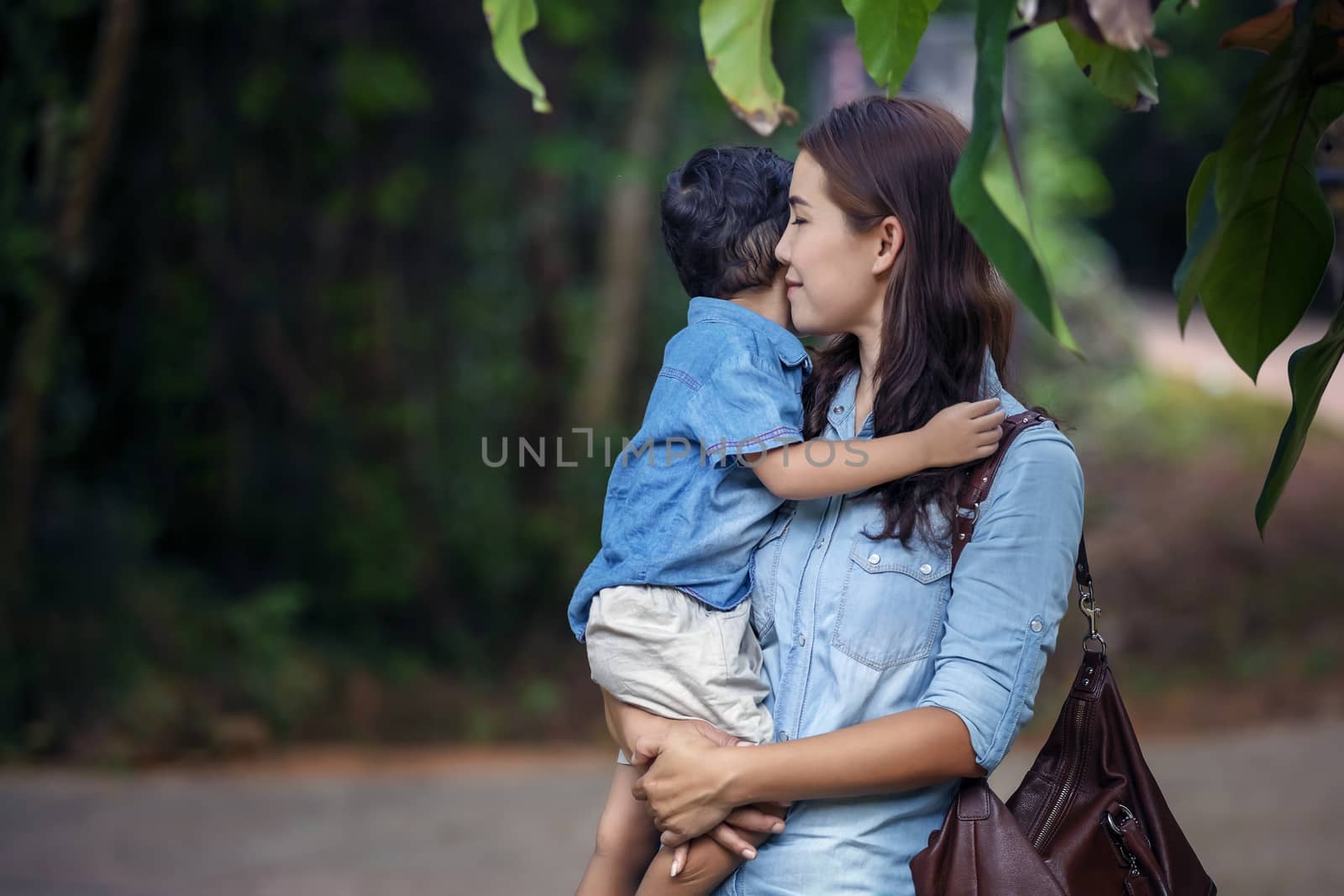 Happy mother and adorable little boy enjoying warm weather at beautiful park