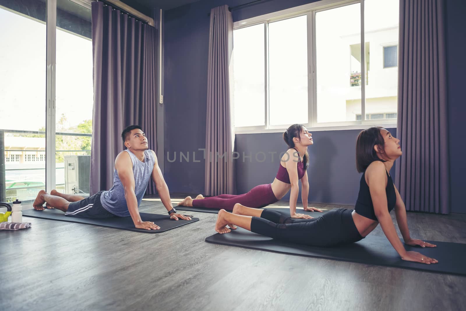 Beautiful woman practicing yoga position and has a close trainer in an indoor gym studio. Healthy and wellness lifestyle concept