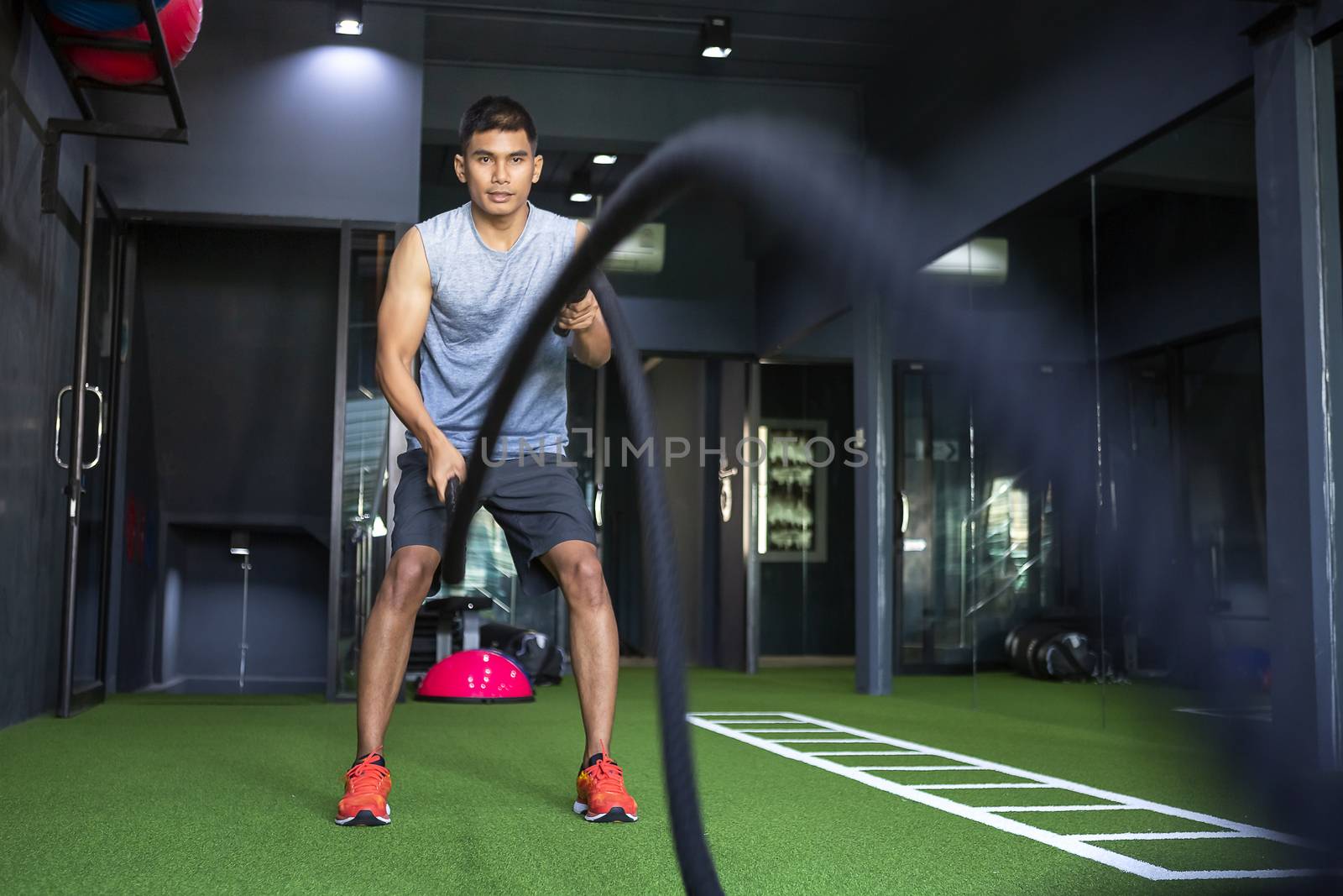 Man wearing a tank top to exercise at the gym with battle ropes  by numberone9018