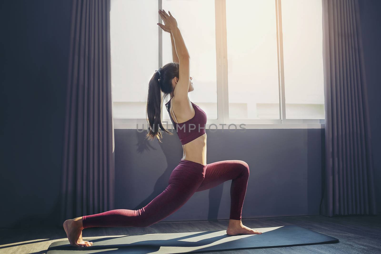 Young sporty woman practicing yoga, doing Purvottanasana exercise, working out, wearing sportswear, Red pants and top, indoor full length