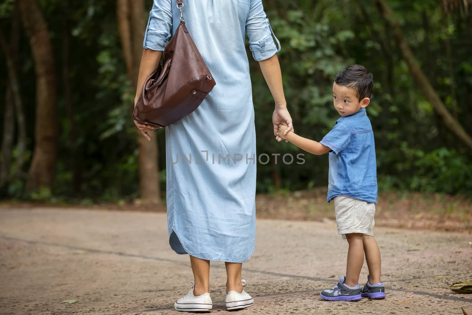 Happy mother and adorable little boy enjoying warm weather at beautiful park