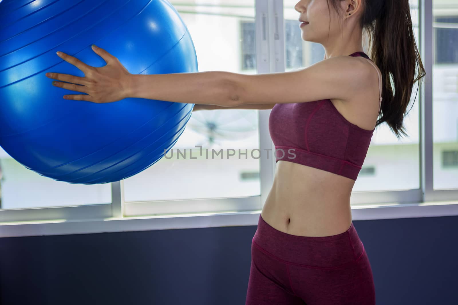 Beautiful woman is exercising by playing Pilates ball happily in by numberone9018