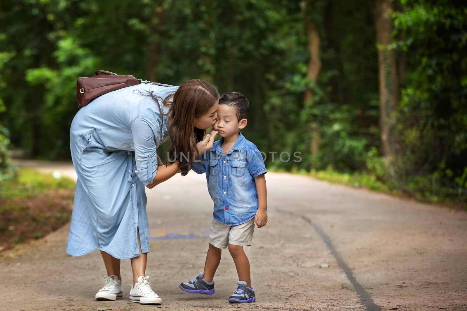 Happy mother and adorable little boy enjoying warm weather at beautiful park