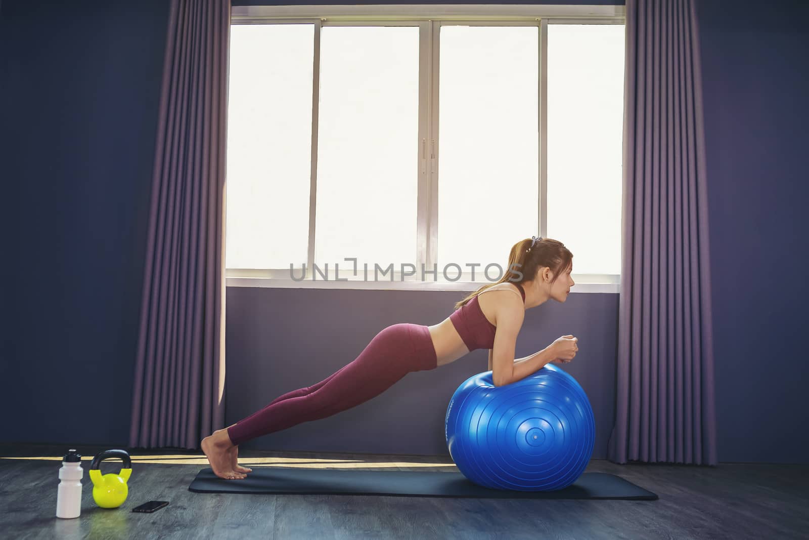 Beautiful woman is exercising by playing Pilates ball happily in by numberone9018