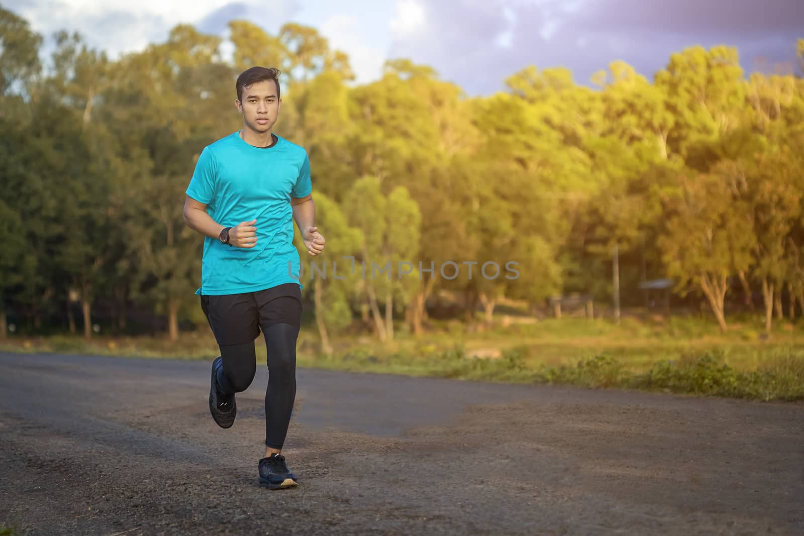 Handsome young man runs for good health on a rural road that is  by numberone9018