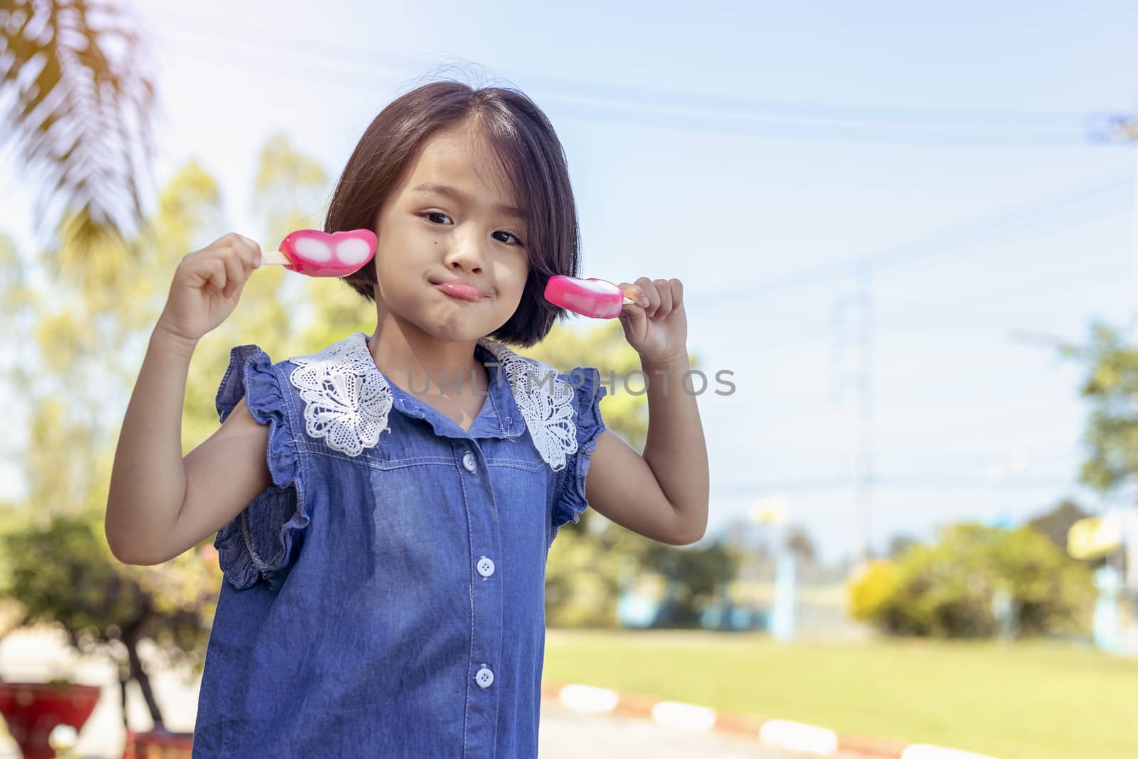 Cute little girl eating popsicle with sunset background