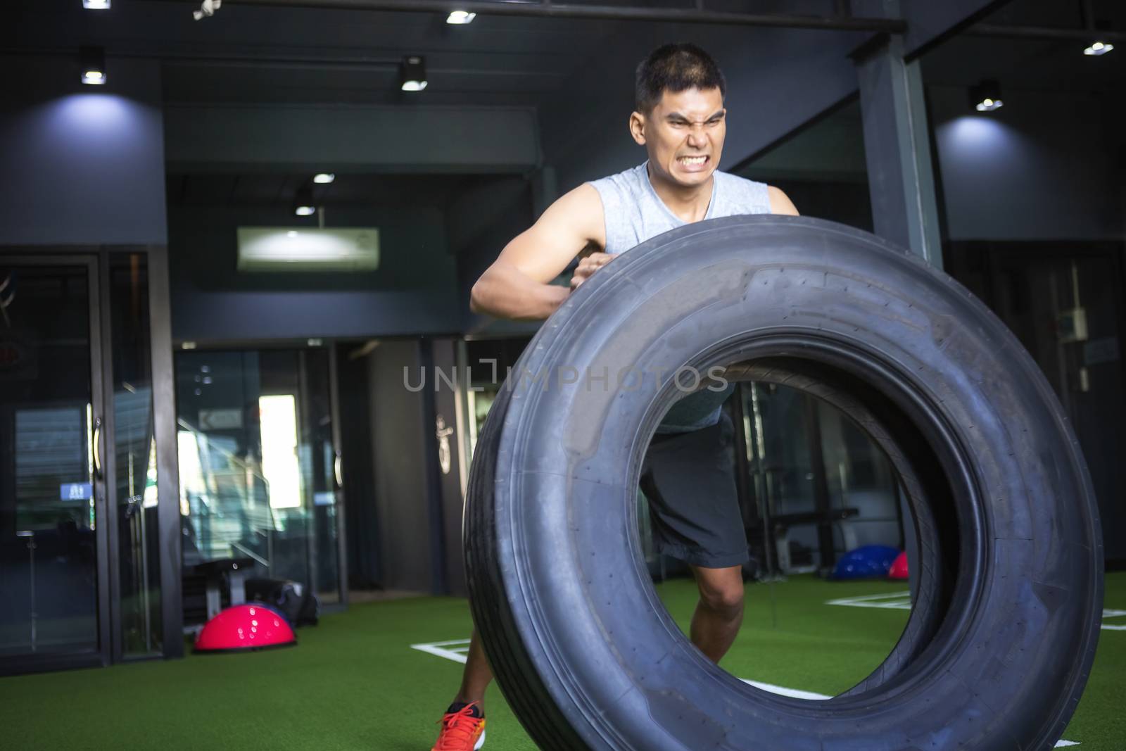 Strong muscular man lifts tire as part of his fitness program. Health fitness concept