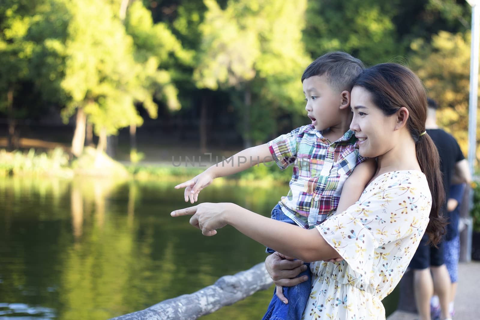 Mother and baby are happy, smiling, enjoying the warm and pure air in a beautiful garden.