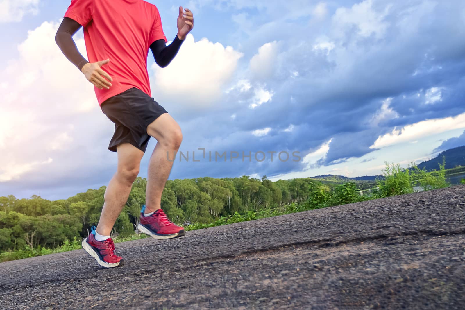 Handsome young man runs for good health on a rural road that is  by numberone9018