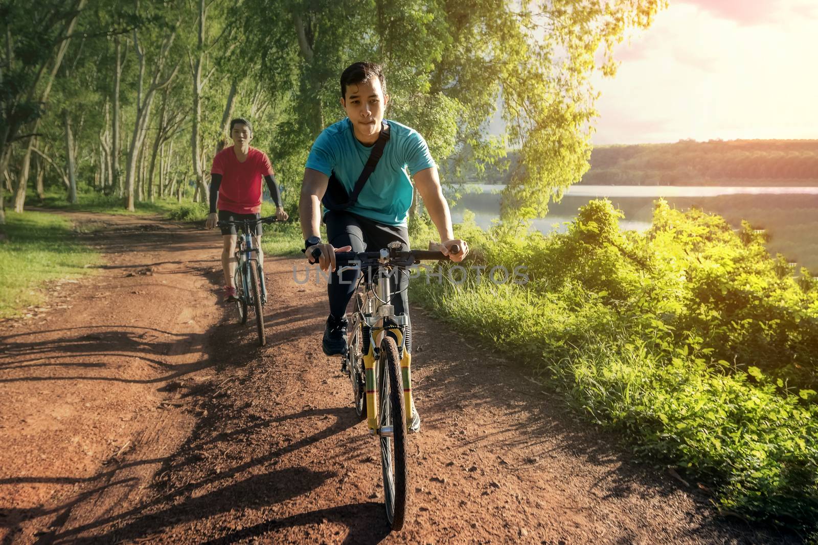 Handsome young man exercising on a bicycle for good health on a rural road that is full of forests and beautiful nature.
