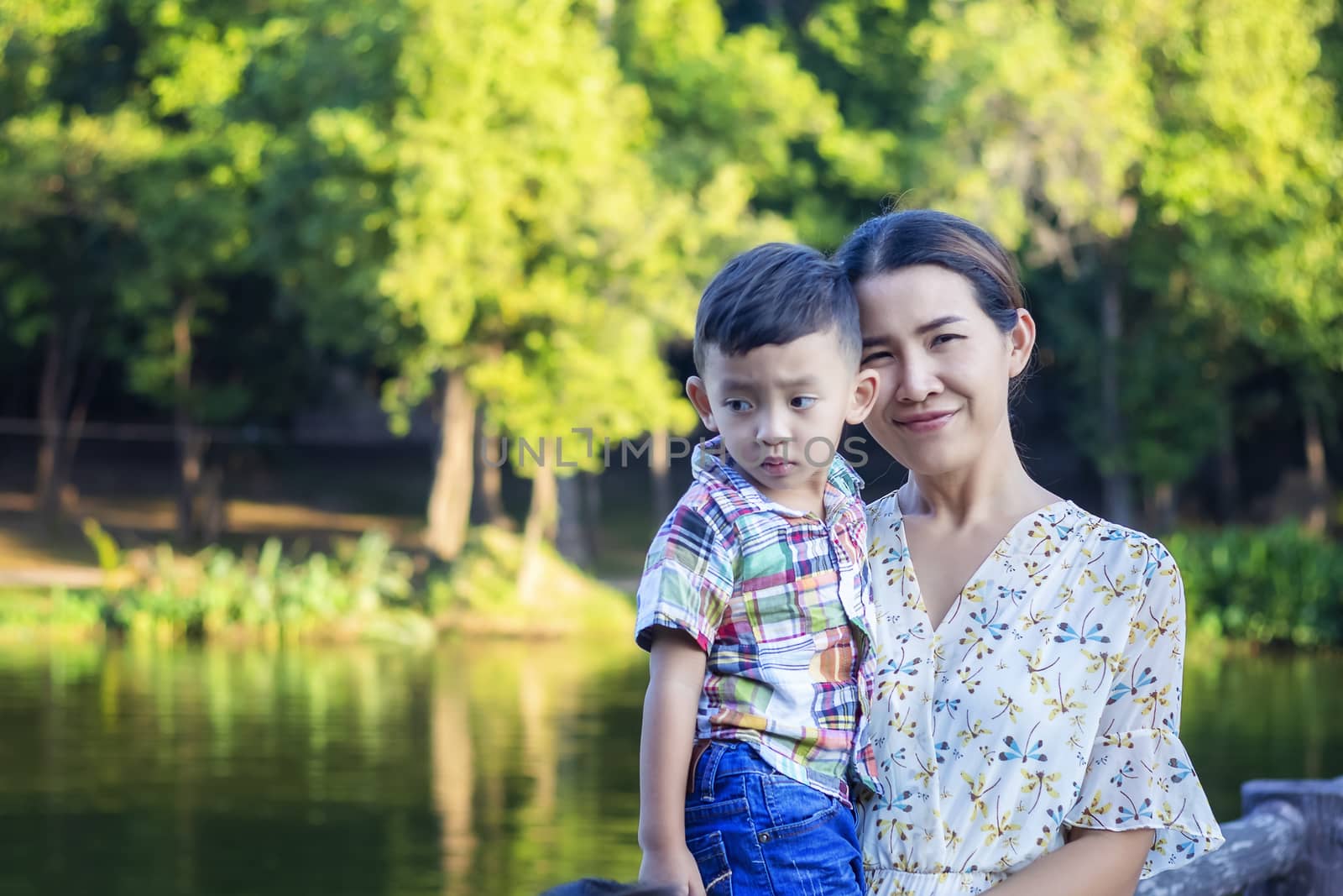 Mother and baby are happy, smiling, enjoying the warm and pure air in a beautiful garden.