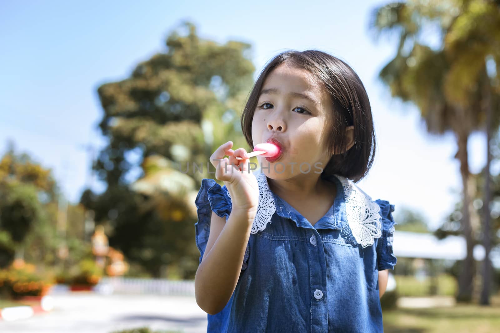 Cute little girl eating popsicle with sunset background by numberone9018