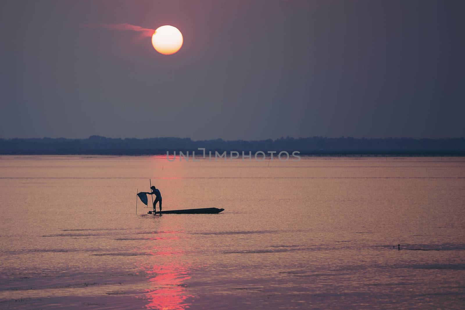 Fishermen make a living by using traps to catch fish that have nets like catching fish during the sunset.