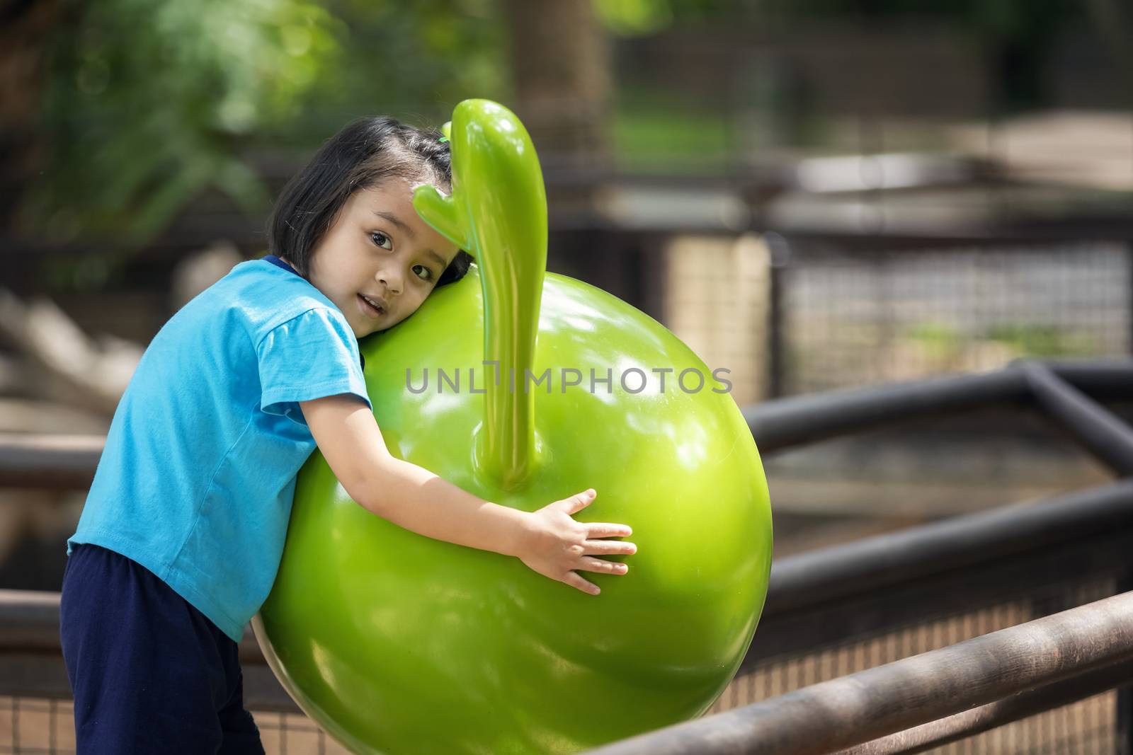 Little beautiful girl happily hugs her beloved mascot in the public garden.