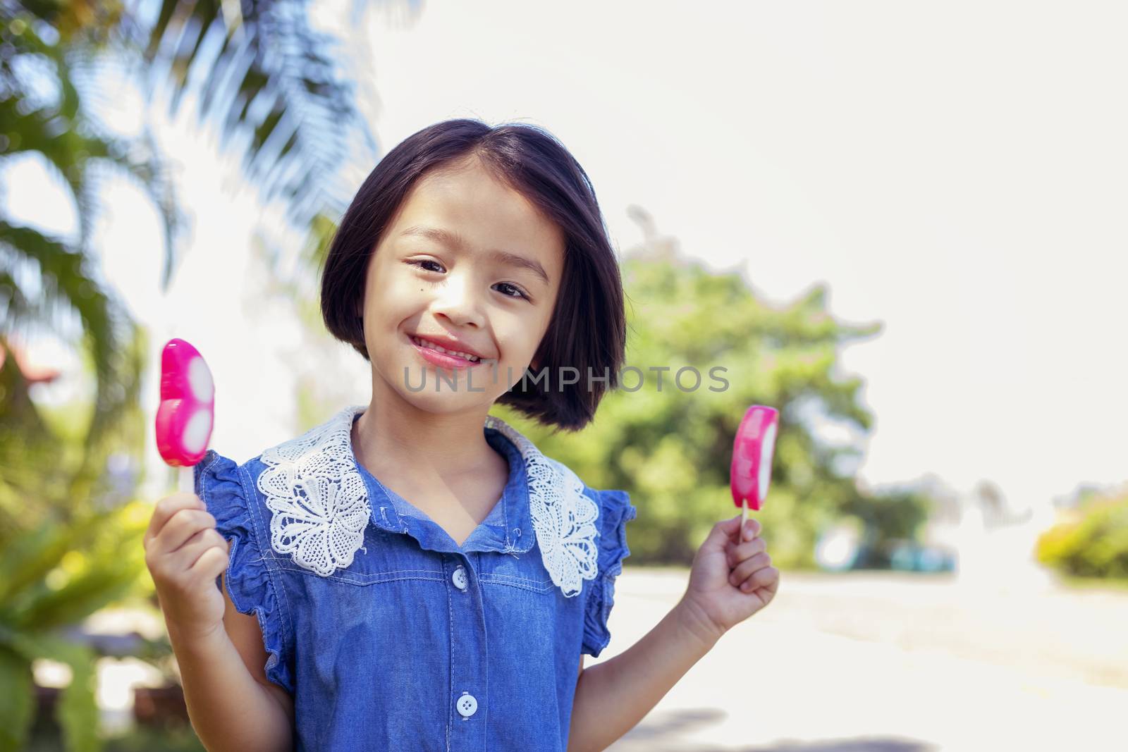 Cute little girl eating popsicle with sunset background