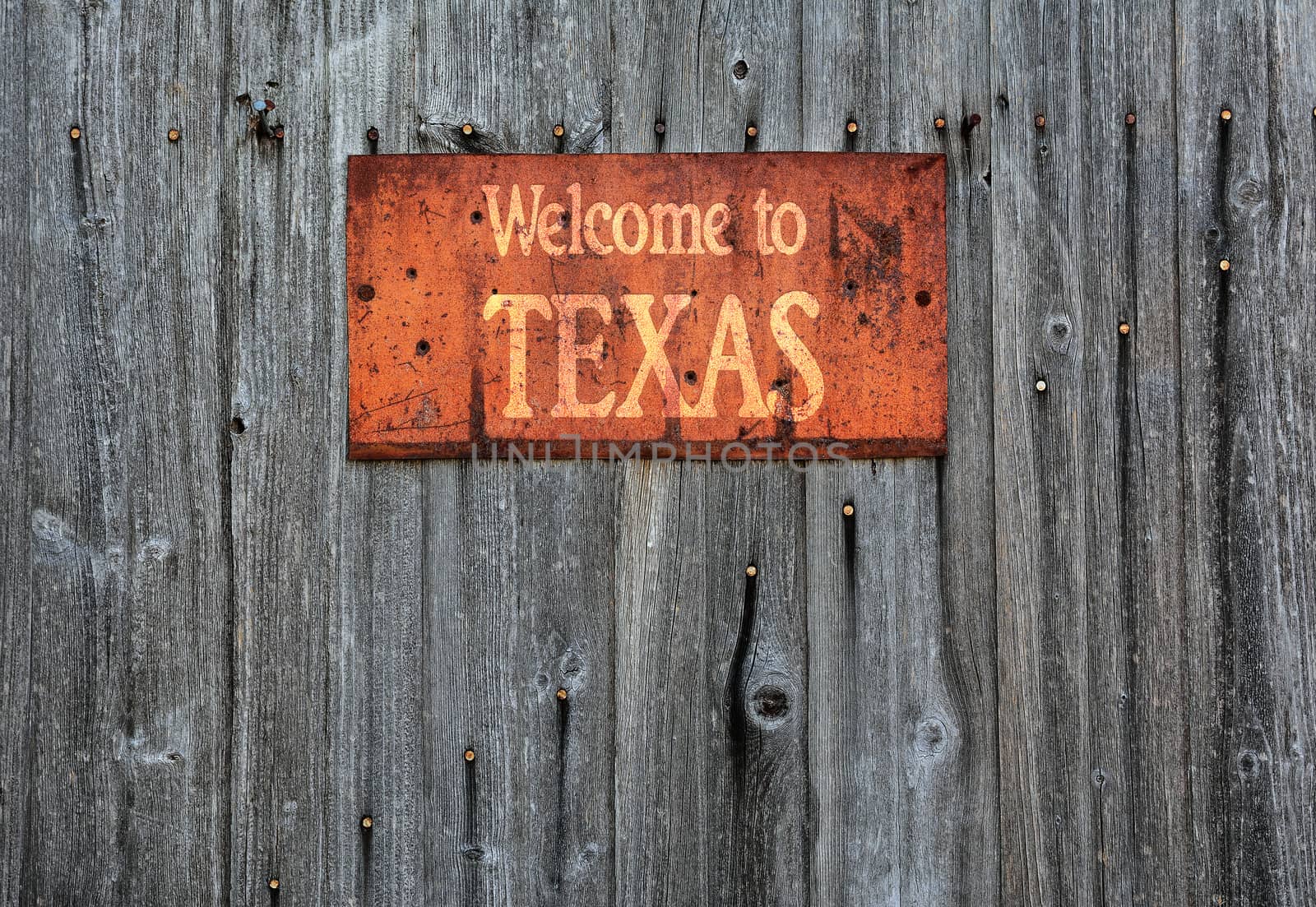 Rusty metal sign on wooden wall with the phrase: Welcome to Texas.