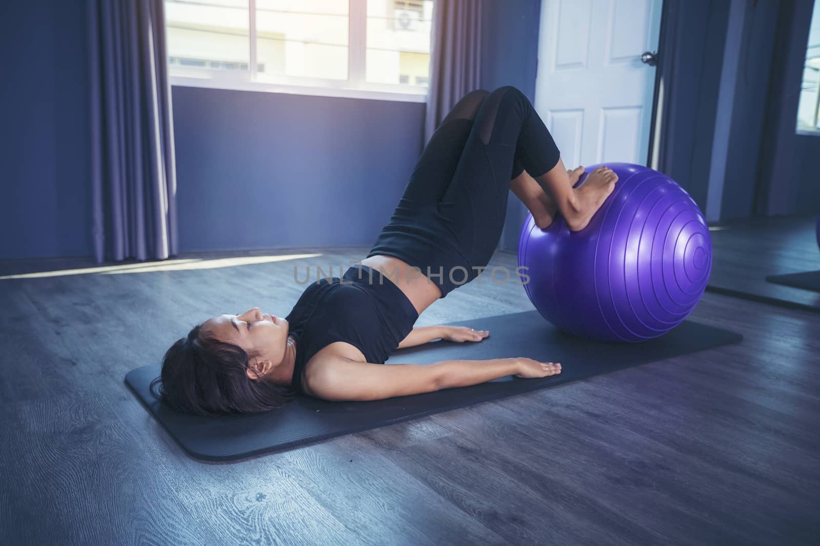Beautiful woman is exercising by playing Pilates ball happily in by numberone9018
