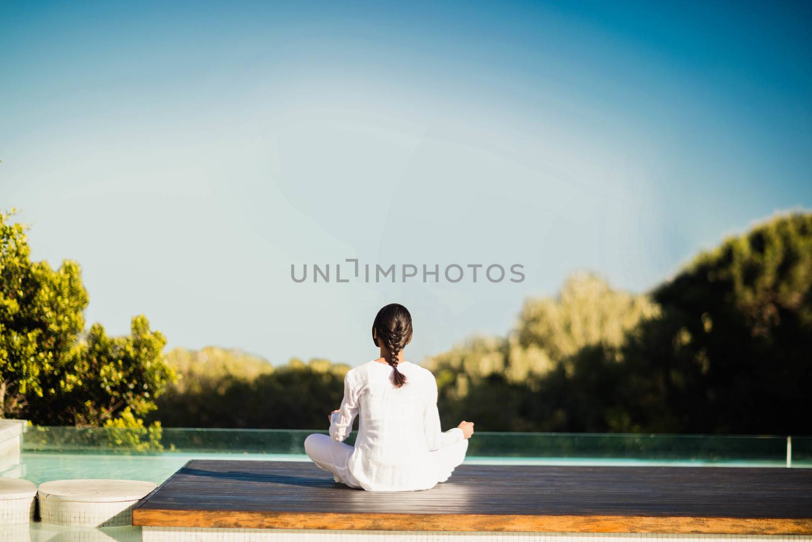 Calm brunette doing yoga by the pool